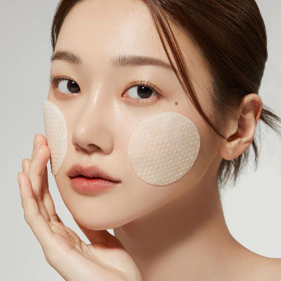 Woman wearing face patches with a neutral background