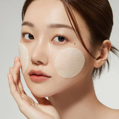Woman wearing face patches with a neutral background
