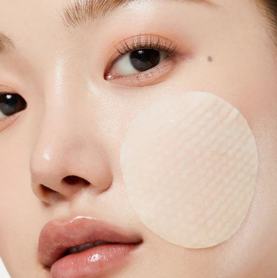 Close-up of a person's face with a patch on one eye, possibly for skincare or cosmetic purposes.