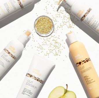 Hair care products with gold glitter and a green apple on a white background
