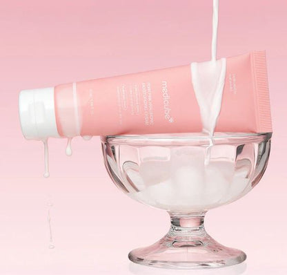 Pink skincare product being poured into a glass bowl against a pink background