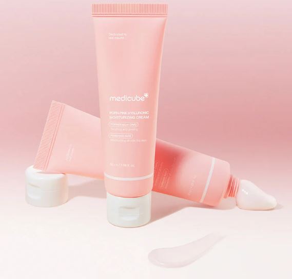 Pink skincare tube with white cap on a pink background