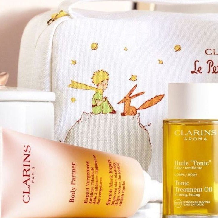 Clarins skincare products including a bottle and tube with a decorative bag in the background.