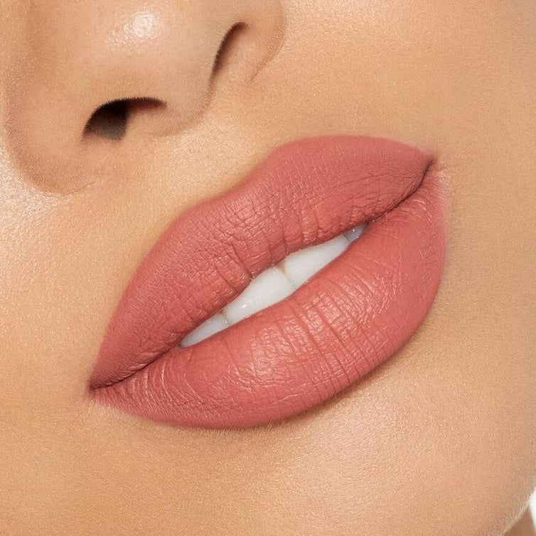 Close-up of a person's lips with a soft pink lipstick on a neutral background