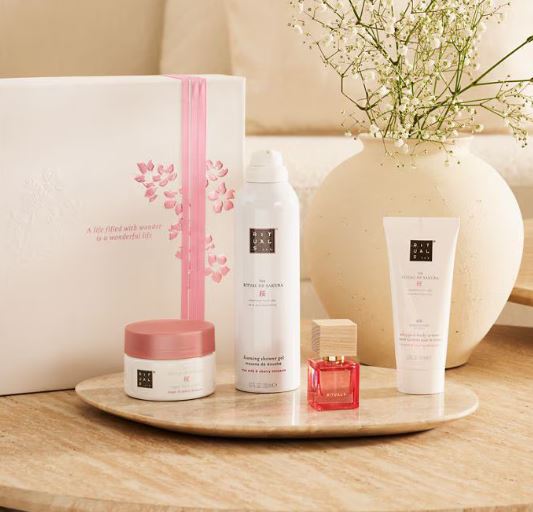 Set of skincare products on a wooden tray with a vase of flowers in the background