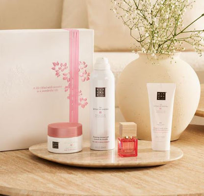 Set of skincare products on a wooden tray with a vase of flowers in the background