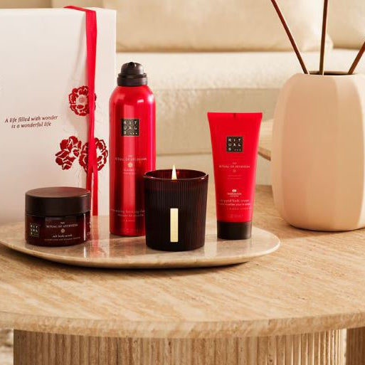 Rituals products including a candle, diffuser, and bottles on a wooden table.