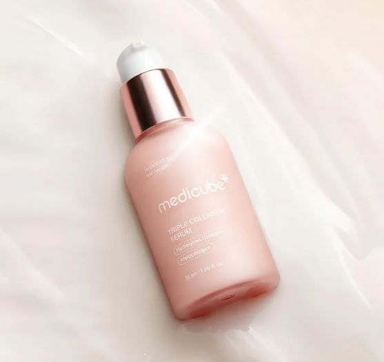Pink skincare serum bottle with rose gold cap on a light pink background