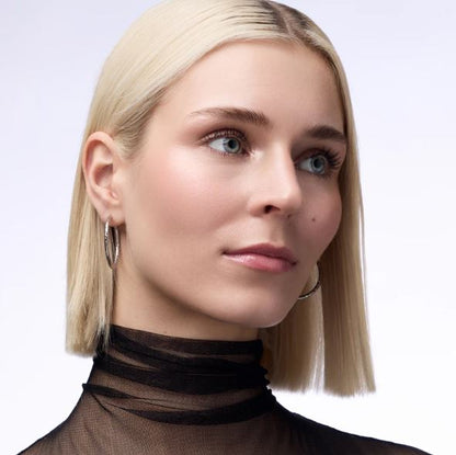 Close-up of a person with blonde hair wearing a brown turtleneck against a white background