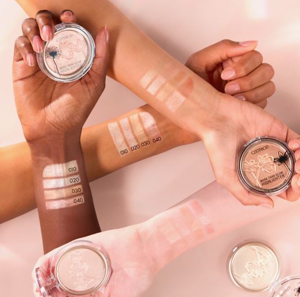 Hands holding makeup products with swatches on a light background