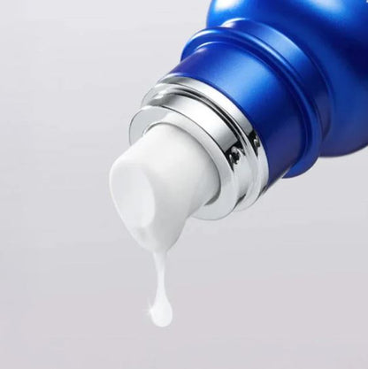 Blue skincare product with white cream being dispensed on a light gray background