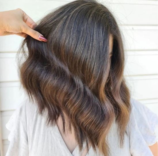 Person with wavy brown hair against a white background