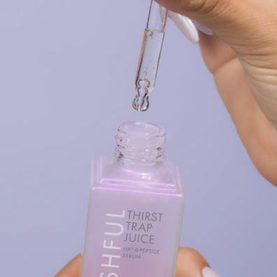 Hand holding a dropper over a bottle labeled 'Thirst Trap Juice' against a light purple background