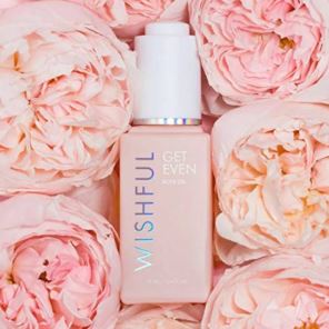 Skincare bottle with 'Wishful' branding surrounded by pink flowers